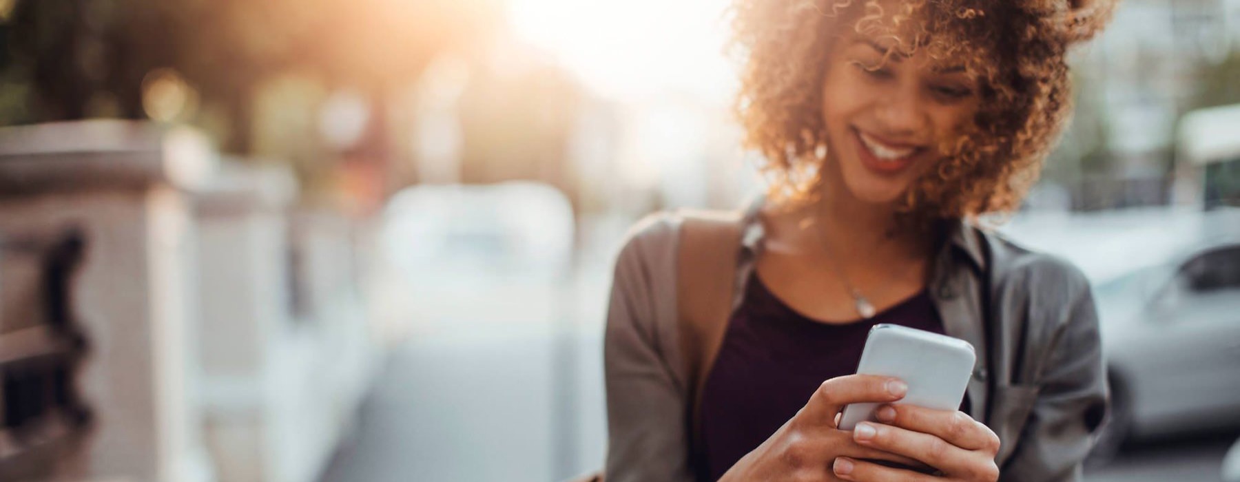 woman texts on her phone as she walks through the city